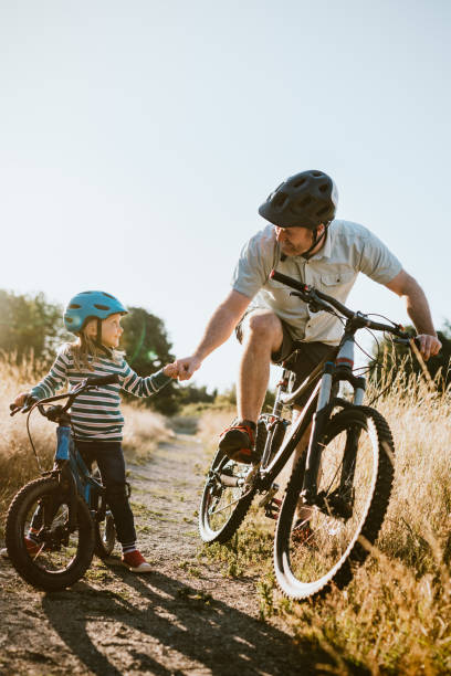 père et descendant vélo de montagne équitation ensemble le jour ensoleillé - family bicycle cycling healthy lifestyle photos et images de collection