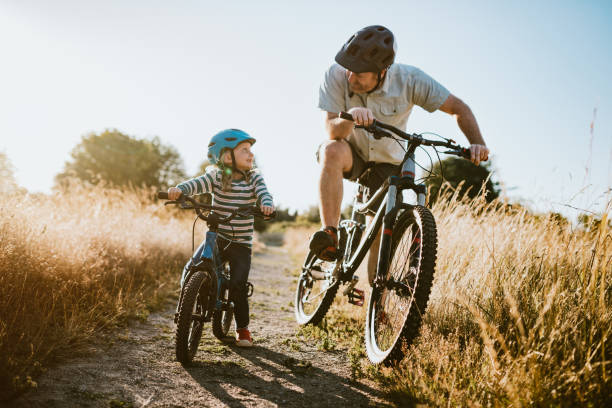 père et descendant vélo de montagne équitation ensemble le jour ensoleillé - family bicycle cycling healthy lifestyle photos et images de collection