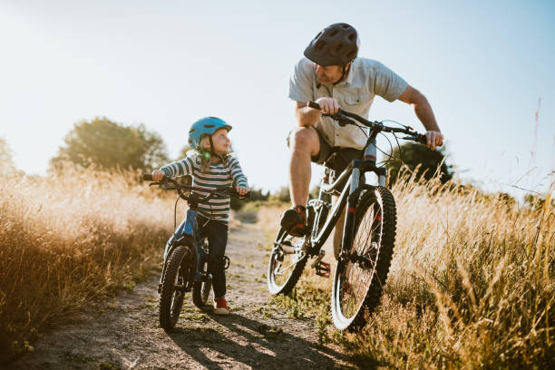 père et descendant vélo de montagne équitation ensemble le jour ensoleillé - recreational pursuit mountain biking nature outdoors photos et images de collection