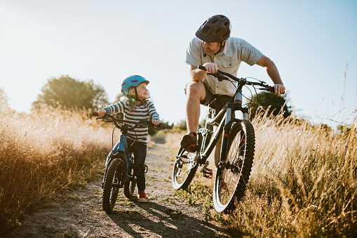 A dad mountain bikes together with his small daughter.  A fun way to spend time together and exercise while on vacation in the Seattle, Washington area.