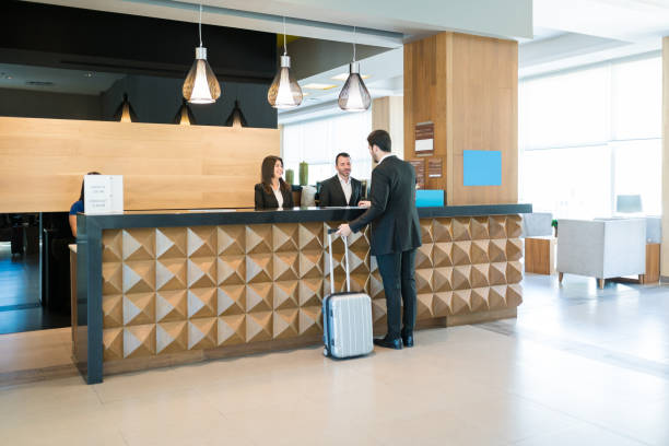 happy hotel clerks are welcoming professional at counter - recepção imagens e fotografias de stock