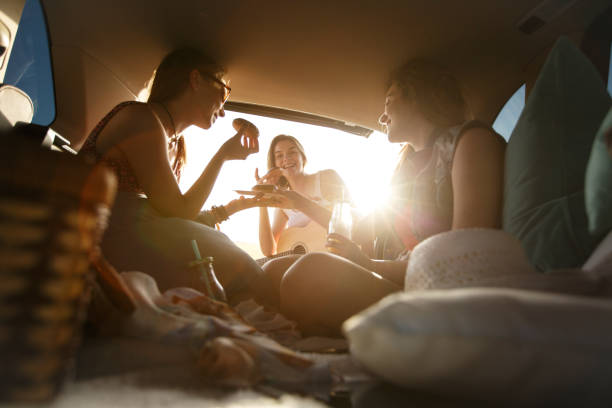 istock Three girlfriends enjoying food and drinks while camping in a vehicle 1164435843