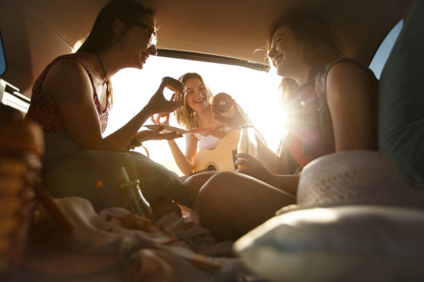 Girlfriends enjoying snacks while camping in a car