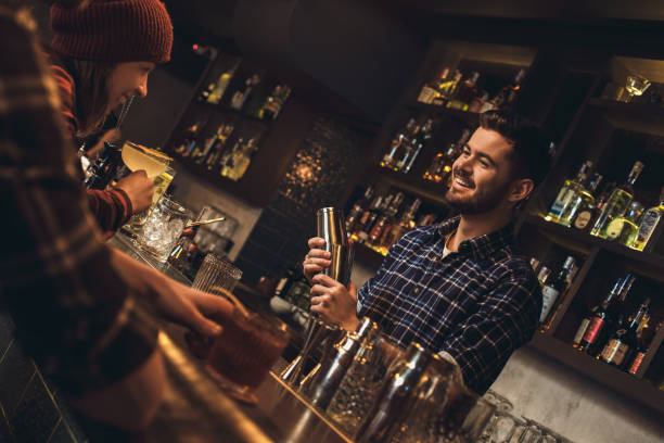 istock Young bartender standing at bar counter talking laughing with visitors cheerful 1164435992