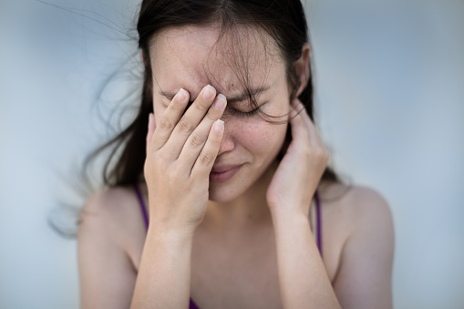 A woman holding her face frustrated and emotional blue tones.