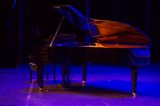 istock baby grand piano on stage lit with blue lighting prior to a performance. 1164440612
