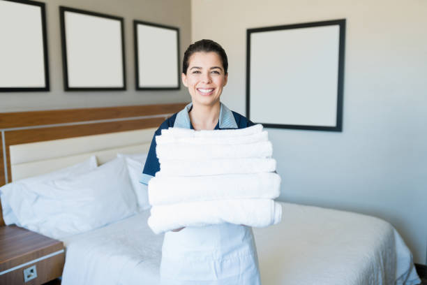 100+ Happy Housekeeper Maid With Stack Of Towels In Hotel Room