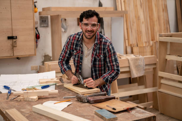 istock Happy carpenter planning the wood at his workshop 1164461146