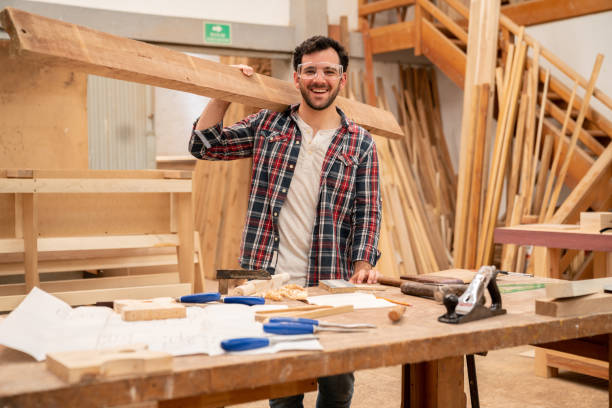 istock Happy carpenter holding wood at the workshop and smiling 1164461166
