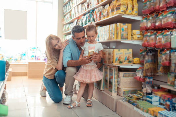 istock Daughter feeling curious while choosing food for parrot with parents 1164461520