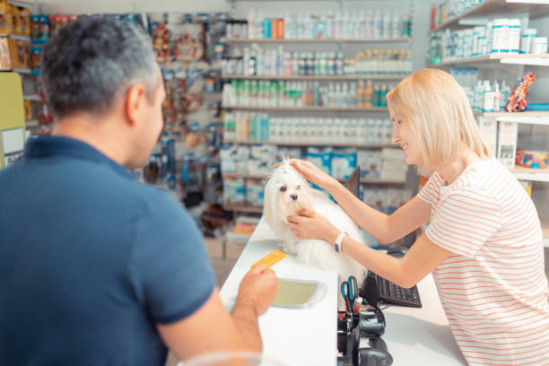 istock Pleasant cashier touching white dog while man paying by card 1164461529