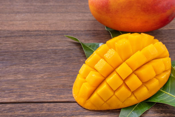 istock Fresh mango - beautiful chopped fruit with green leaves on dark wooden timber background. 1164463149