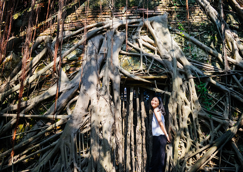 Single young Asian girl smile to camera standing before the famouse old tree house at Anping, Taiwan