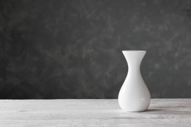 istock white vase on wooden table on black background 1164474315