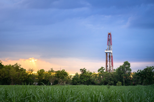 Oil field, Onshore drilling rig is drilling downhole to explore crude oil in Petroluem industrial business. The rig is operate on land in countryside area, so it arounded with beautiful agriculture field and sunlight from evening time.