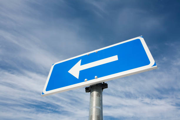 istock traffic sign arrow pointing left against sky 1164479465