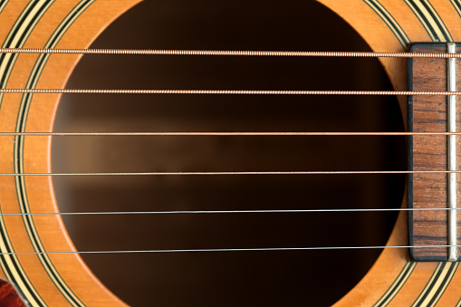 close macro view of the six frets  and sound hole on an acoustic wooden  guitar