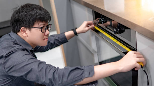 istock Asian man using tape measure on oven 1164484129