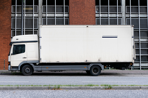 Hamburg, Germany - July 21. 2019: Side view of an old white, dirty truck, without advertising attached, parked somewhere in Hamburg on the street. The vehicle is parked in the residential area after work.