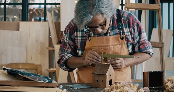 Asian senior carpenter working in his workshop, Bangkok Thailand, Working at Home, Small Business Concept