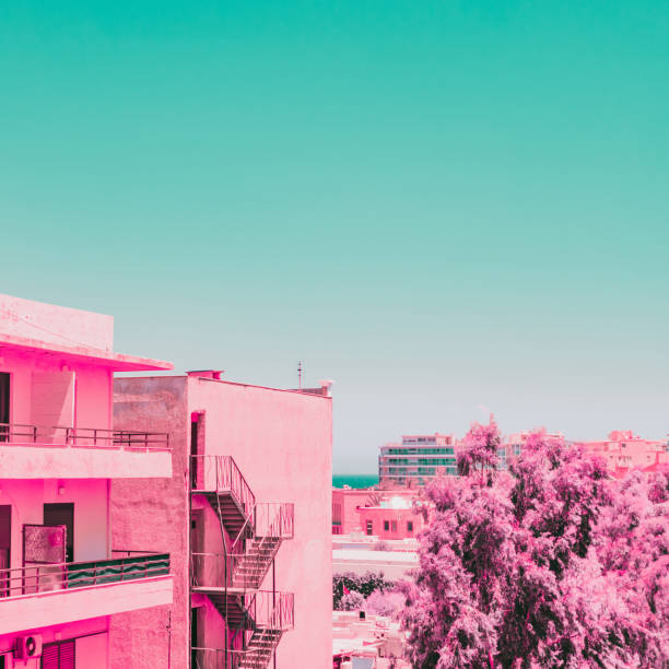 blick auf die neue stadt am meer. tropische und exotische lage. infrarot rosa stil. ozean - pink buildings stock-fotos und bilder