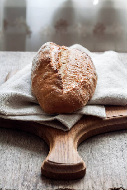 istock Loaf of whole wheat bread wooden board on kitchen table 1164495261