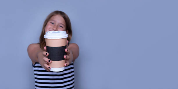 Smiling girl giving, showing coffeecup closeup side view