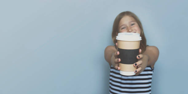Smiling girl giving, showing coffeecup closeup side view