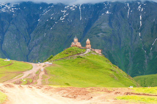 panoramablick auf die dreifaltigkeitskirche (tsminda sameba) unter dem berg kazbegi in stepantsminda, georgia. - kazbek stock-fotos und bilder