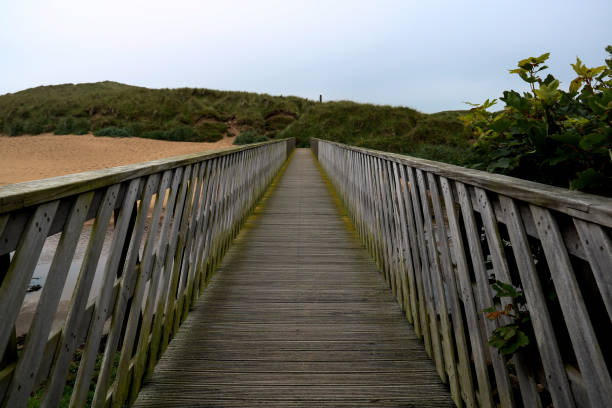 деревянный пешеходный мост над устьем реки к пляжу - cruden bay стоковые фото и изображения