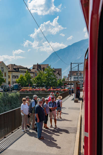 trem vermelho rhatian pára em chur para pegar os passageiros ao longo da linha cênico chur-arosa - rhätische bahn - fotografias e filmes do acervo