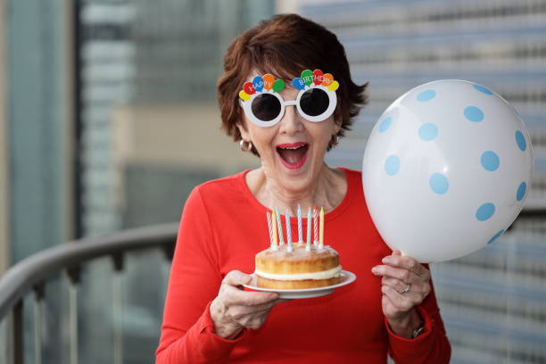 smiling woman with happy birthday glasses holding a cake and balloon. - personal accessory balloon beauty birthday imagens e fotografias de stock