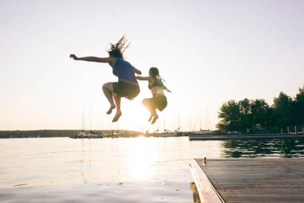 istock Summer day: young adults jump from jetty into lake 1164509200