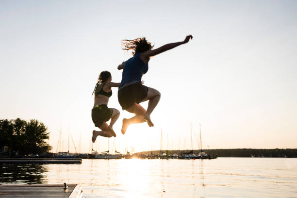 istock Summer day: young adults jump from jetty into lake 1164509214
