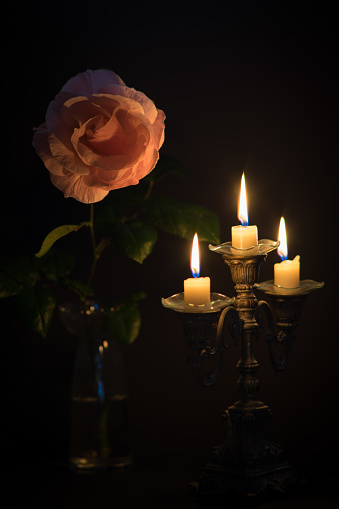 Rose with candles, surrounded by darkness. Maybe a funeral.