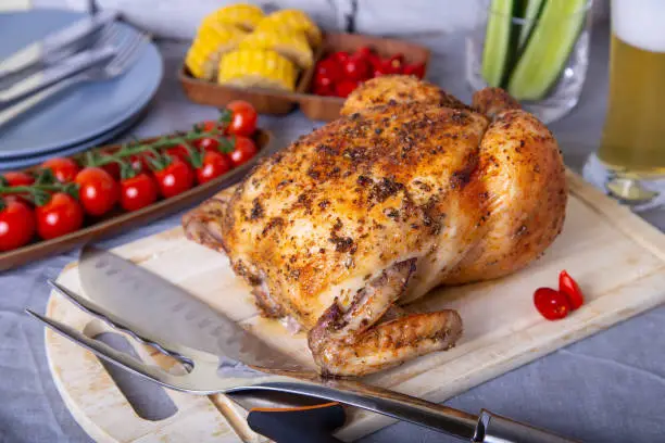 Whole chicken baked in salt. With corn, tomatoes, cucumbers and jalapeno peppers. Selective focus, close-up.