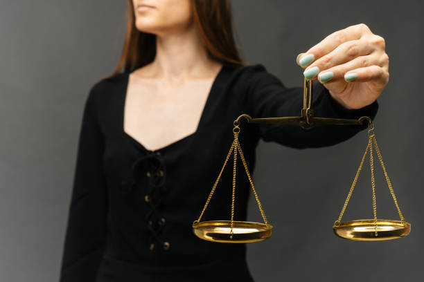 istock Serious woman holding the justice scale on dark background 1164520804