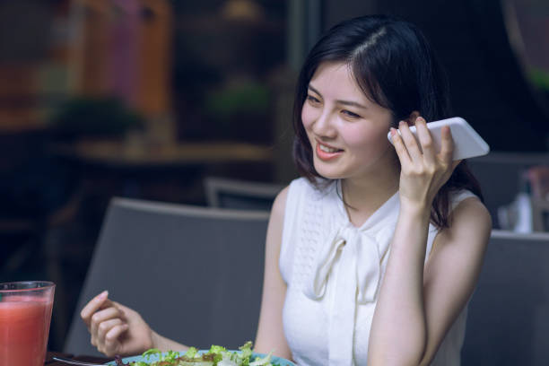 istock Beautiful Asian young woman having healthy breakfast in modern restaurant and using mobile phone 1164521005