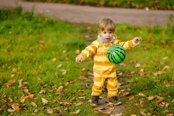 Concept: family, kids. Happy little child, baby boy laughing and playing with green ball in the autumn on the nature walk outdoors at park