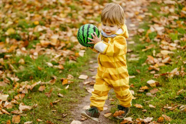Concept: family, kids. Happy little child, baby boy laughing and playing with green ball in the autumn on the nature walk outdoors at park