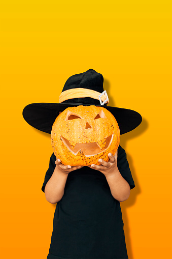 Halloween 2019 holiday concept. Cute little kid with carved pumpkin. Happy little boy holding a big Halloween pumpkin. Copy space for text