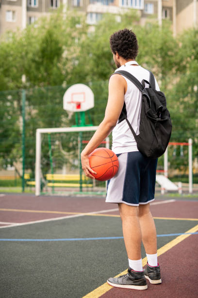 istock Young active male basketball player with ball and backpack on playground 1164525193
