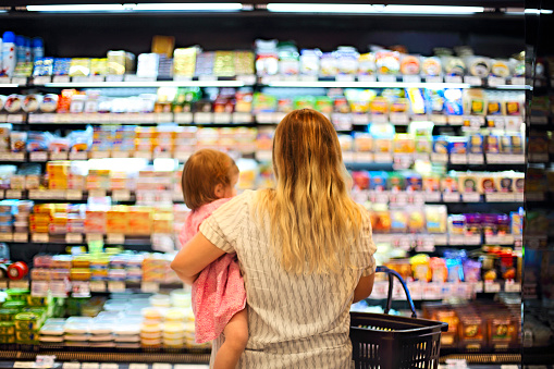 Cheerful mother and baby spending time in shopping in supermarket, shallow depth of field