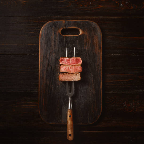 Three pieces of meat on a fork for meat stock photo
