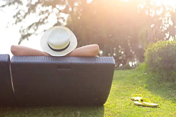 Relaxed woman in the hat sitting at the beach at sunset time