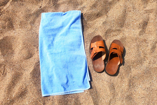 istock Men's slippers and a towel on the sand. 1164530906