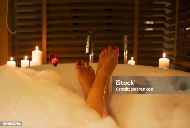 Feet Of The Young Woman In Bath With Foam And Candles Stock Photo - Download Image Now