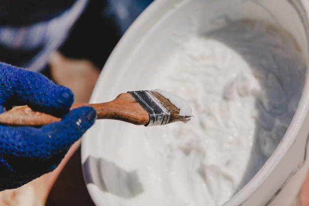 istock Gloved hand is picking up on brush white building mass 1164538141