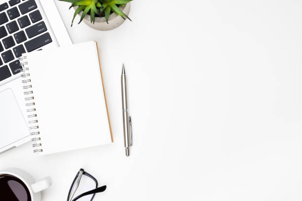 istock Blank small notebook page is on top of white office desk table with pen, laptop computer and supplies. Top view with copy space, flat lay. 1164539656