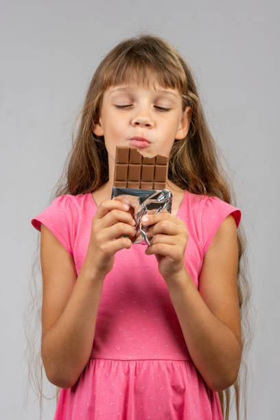 istock Eight-year-old girl with pleasure eats chocolate bar 1164544520